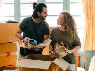A cheerful couple unpacking boxes in their new apartment, smiling at each other.